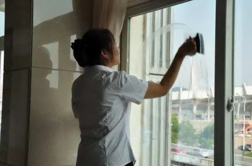 保洁阿姨正在用专业工具擦拭玻璃